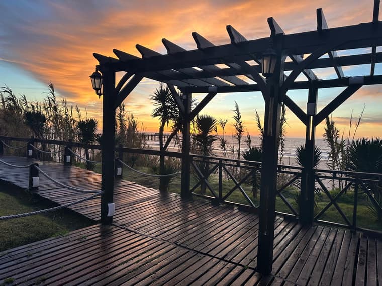 Deck con pérgola frente al mar al atardecer