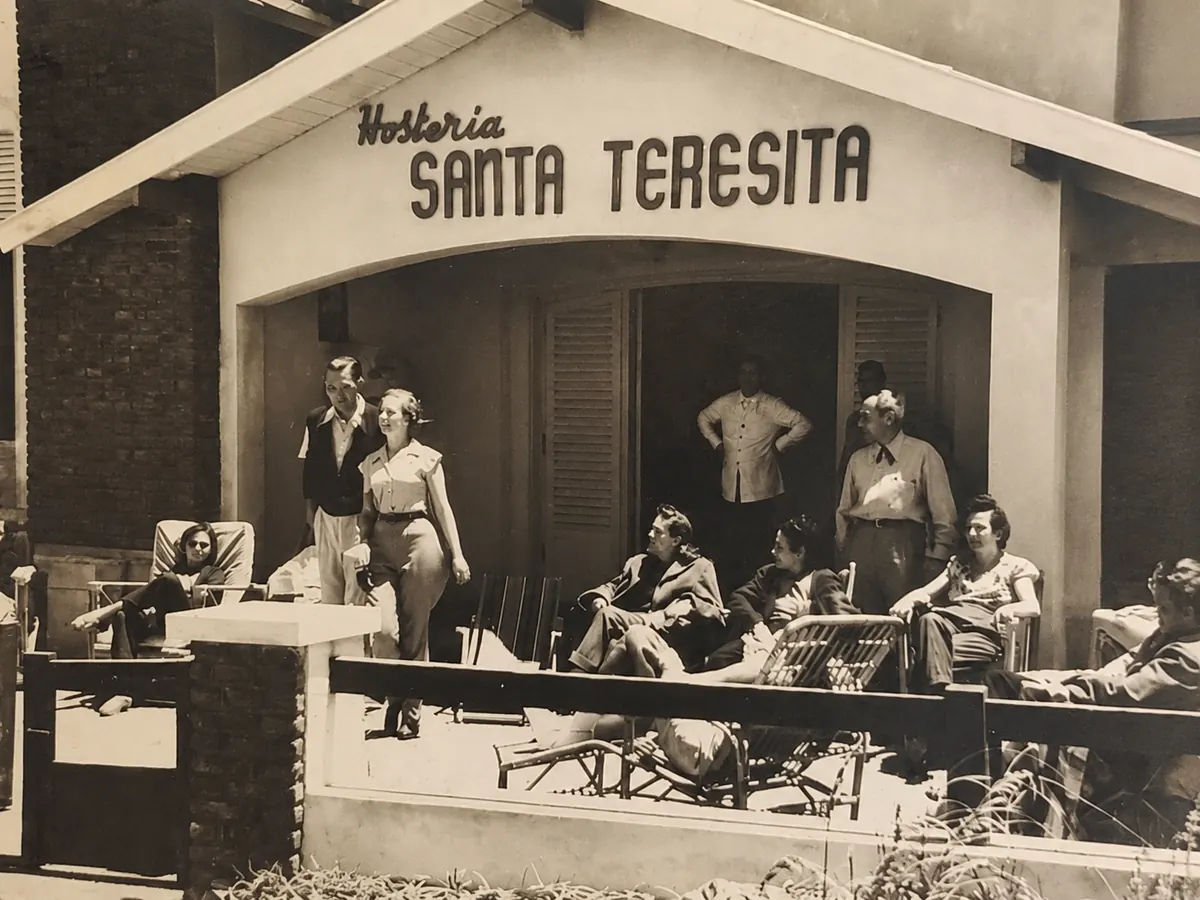 Huéspedes en la galería de la Hostería Santa Teresita, bajo el cartel con su nombre, en una foto de época